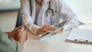 A photo of a doctor showing a patient information on a digital tablet.